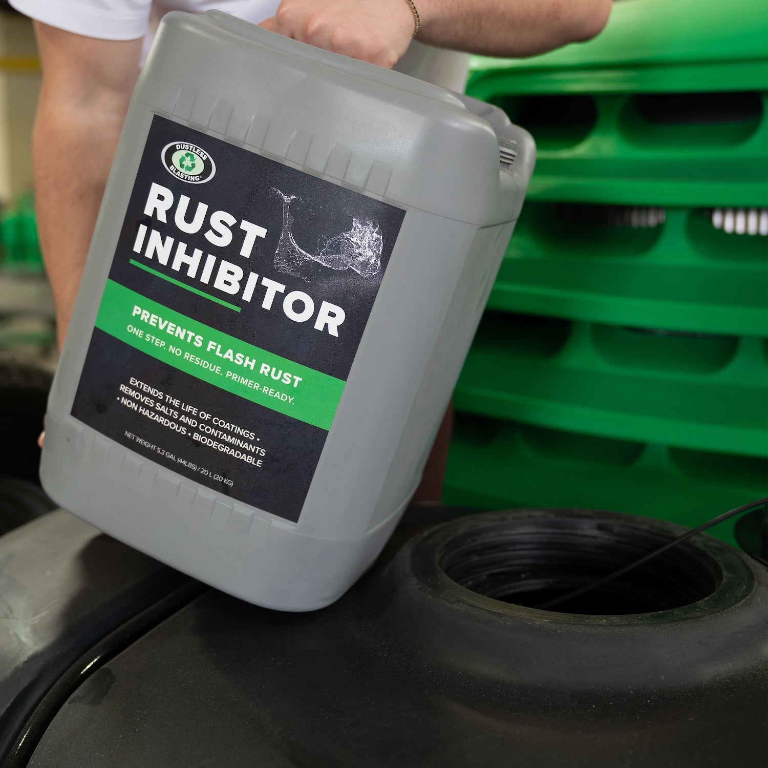 Pouring 5 gal container of Dustless Blasting rust inhibitor into the water tank of a mobile machine to help prevent flash rust for up to 72 hours. 